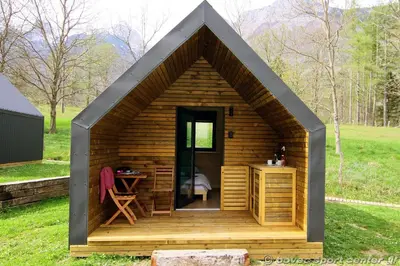 a small wooden cabin with a desk in a field at Glamping Virje in Bovec