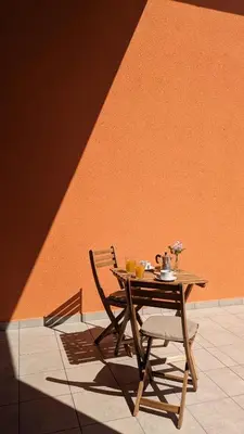 a wooden table and chair next to an orange wall at Nono Apartment in Renče