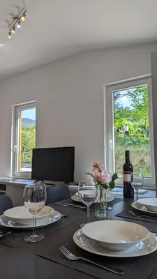 a table with plates and glasses and a bottle of wine at Nono Apartment in Renče