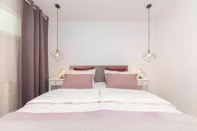 a bedroom with a large white bed with pink pillows at DSE Apartment in Celje