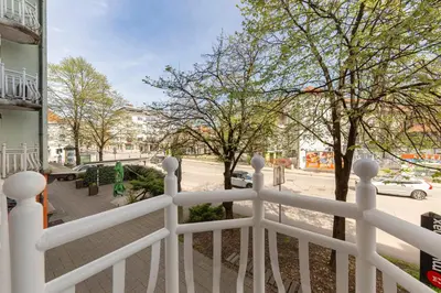 a white fence in front of a street with trees at DSE Apartment in Celje