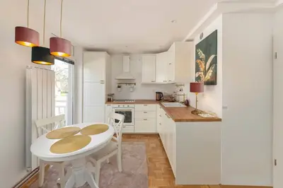 a kitchen with white cabinets and a white table and chairs at DSE Apartment in Celje