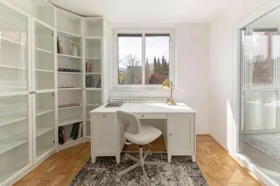 a white desk with a chair in a room with shelves at DSE Apartment in Celje