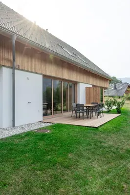 a house with a deck with a table and chairs at House Natura Savica in Bohinj