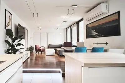 a kitchen and living room with white walls and blue chairs at Matic Murgle Atrium Apartment in Ljubljana