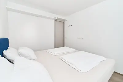 two beds in a white room with white pillows at Matic Murgle Atrium Apartment in Ljubljana