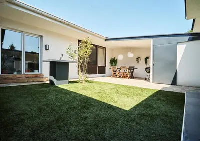 a backyard with green grass and a house at Matic Murgle Atrium Apartment in Ljubljana