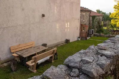 a wooden bench sitting next to a wall with rocks at Krasna Hiška - Authentic Heritage Home in Sežana