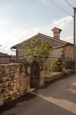 a brick house with a stone wall and a tree at Krasna Hiška - Authentic Heritage Home in Sežana