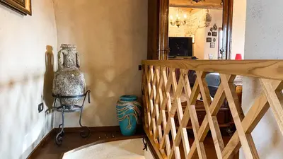 a hallway with a wooden staircase and a mirror at Krasna Hiška - Authentic Heritage Home in Sežana