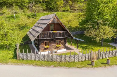 a small wooden house on a hill with a fence at Organic Homestead Mikl in Slovenj Gradec