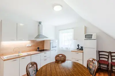 a kitchen with white cabinets and a table and chairs at Apartment Pr' Štajercu with Free Onsite Parking in Bovec