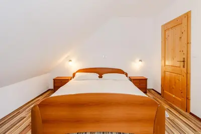 a bedroom with a wooden bed and a wooden door at Apartment Pr' Štajercu with Free Onsite Parking in Bovec