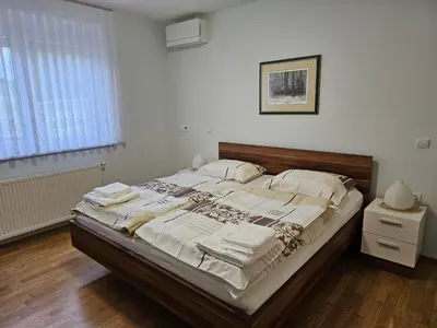 a bedroom with a large bed with a wooden headboard at Hišica ob Potoku in Podčetrtek