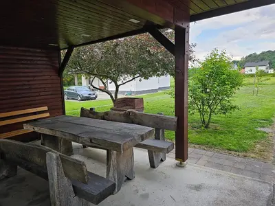 a wooden picnic table sitting under a pavilion at Hišica ob Potoku in Podčetrtek
