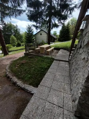 a concrete walkway leading to a park with a bench at Počitniška hiša Lokve in Trnovo