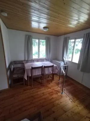 a dining room with a table and two windows at Počitniška hiša Lokve in Trnovo