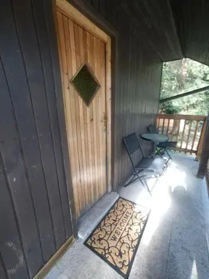a front door of a cabin with a table and a bench at Počitniška hiša Lokve in Trnovo