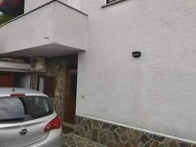 a white building with a car parked next to it at Zala Apartment in Zgornje Škofije