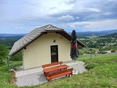 a small building with a bench and an umbrella at Vineyard cottage foggy sea in Semič
