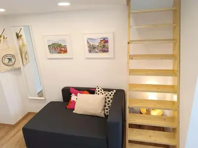 a living room with a black couch and a staircase at One-bedroom city apartment in Ljubljana