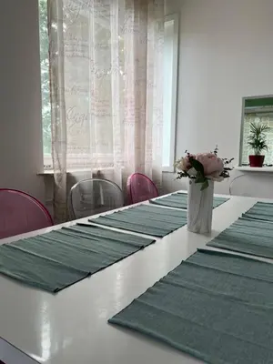 a long table with green mats and a vase of flowers on it at Apartment Ljubljana - Free parking in Ljubljana