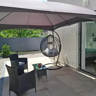 a swing and chairs under an umbrella on a patio at Downtown Delight in Ljubljana