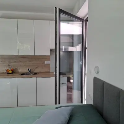 a kitchen with white cabinets and a bed in a room at Downtown Delight in Ljubljana