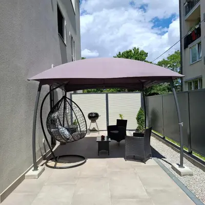 a purple umbrella on a patio with chairs and a swing at Downtown Delight in Ljubljana