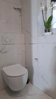 a white bathroom with a toilet and a vase with flowers at Downtown Delight in Ljubljana