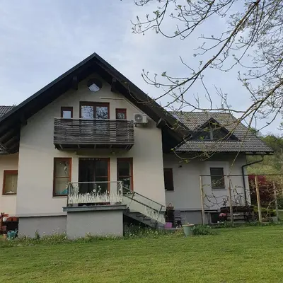 a white house with a balcony and a yard at River House Radolca in Radovljica