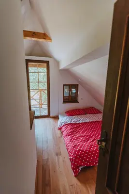 a bedroom with a red bed in a attic at Brunarica Dežno in Makole
