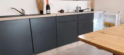 a kitchen with black cabinets and a sink and a table at Apartment with a view in Dobravlje