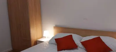 a bedroom with a bed with two red pillows on it at Apartment with a view in Dobravlje
