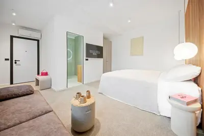a white bedroom with a bed and a couch at Bugabu Ljubljana in Ljubljana