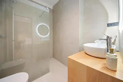 a white bathroom with a sink and a shower at Bugabu Ljubljana in Ljubljana