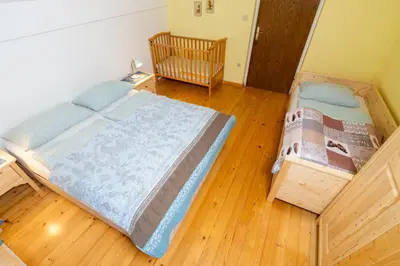 a bedroom with a crib in a room with wooden floors at Apartments Dominika Štros in Bohinj