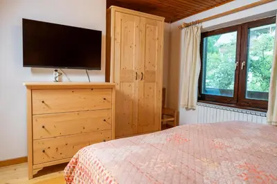 a bedroom with a bed and a dresser with a television at Apartments Dominika Štros in Bohinj