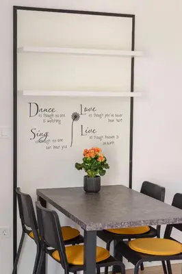 a table and chairs in a room with a wall at Apartma Lajf in Brežice