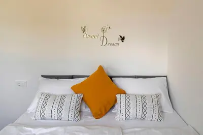 a bed with three pillows and a sign on the wall at Apartma Lajf in Brežice