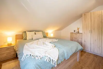 a bedroom with a bed with a blue blanket on it at Forest Breeze Apartments in Blejska Dobrava