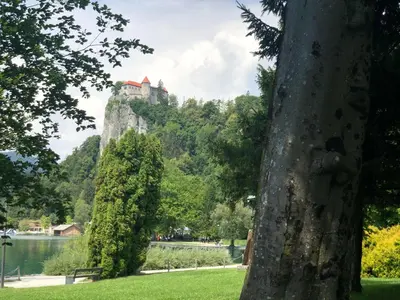 a castle on top of a mountain next to a lake at Forest Breeze Apartments in Blejska Dobrava
