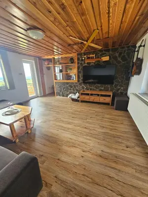 a living room with wood floors and a flat screen tv at TRUTH WINES HOUSE in Veliki Vrh
