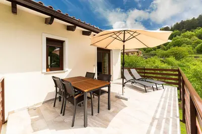 a patio with a wooden table and chairs and an umbrella at Brkinka Apartments in Vremski Britof