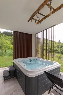 a hot tub in a room with a large window at Brkinka Apartments in Vremski Britof