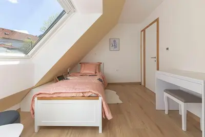 a attic bedroom with a bed and a window at Apartma pri Jakobu in Postojna