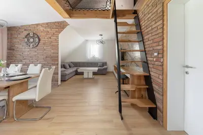 a loft conversion with a brick wall and a spiral staircase at Apartma pri Jakobu in Postojna