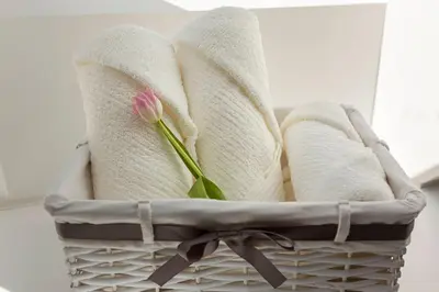 a pink flower sitting in a basket with towels at Apartma pri Jakobu in Postojna