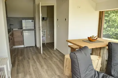 a kitchen and living room with a wooden table at Hiška ob gozdu Lukez plac in Ljubno