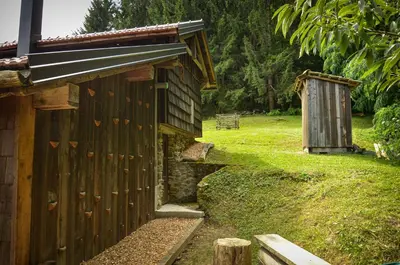 a wooden building with a bench in a field at Hiška ob gozdu Lukez plac in Ljubno